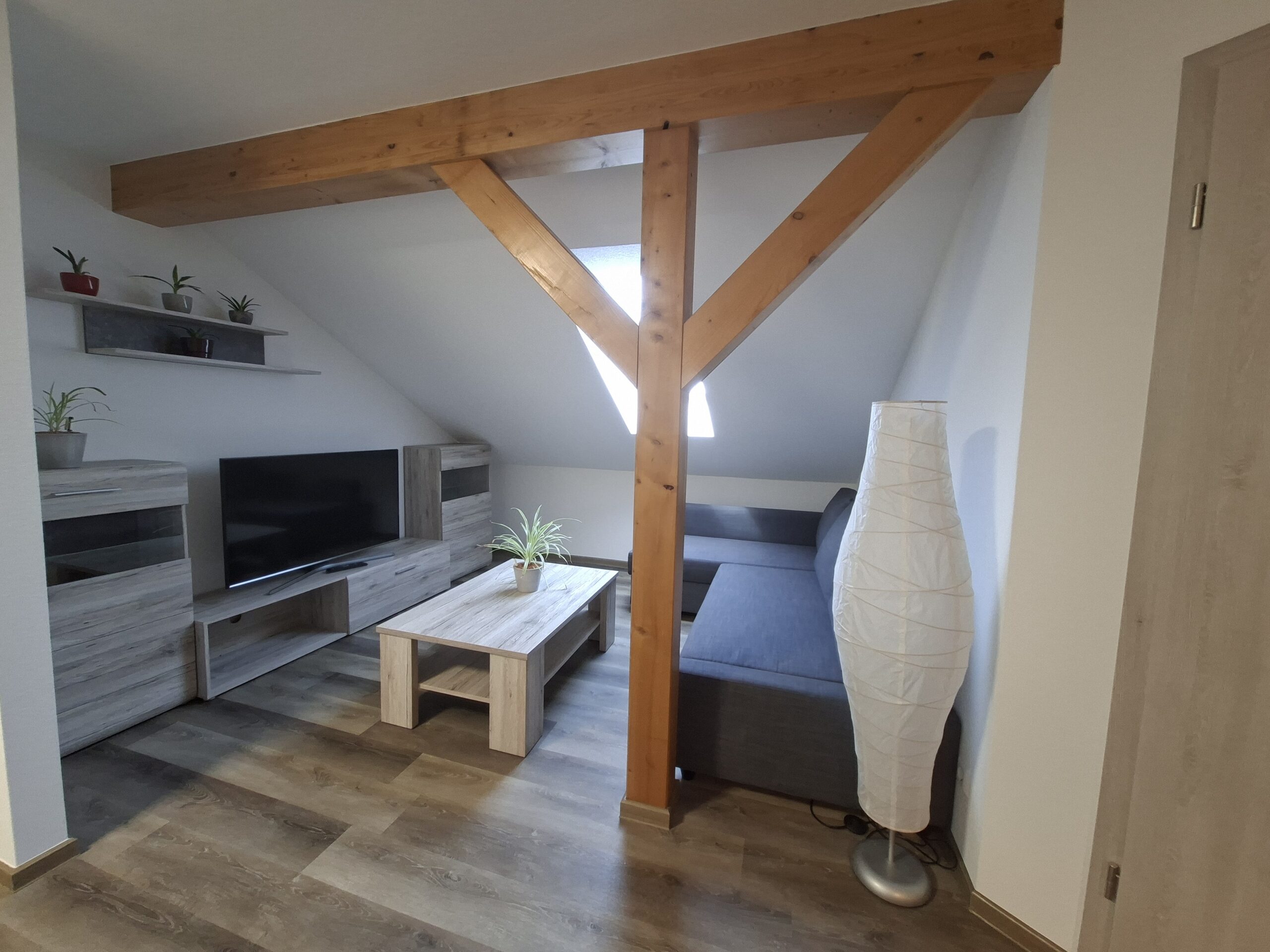 Wohnbereich mit Sofaecke und Holzbalken in Appartement 2